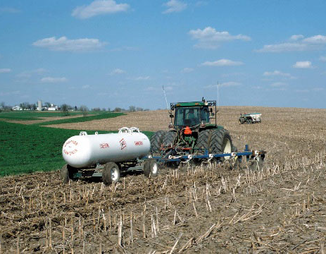 Tractor on the field applying fertilizer from a tank.