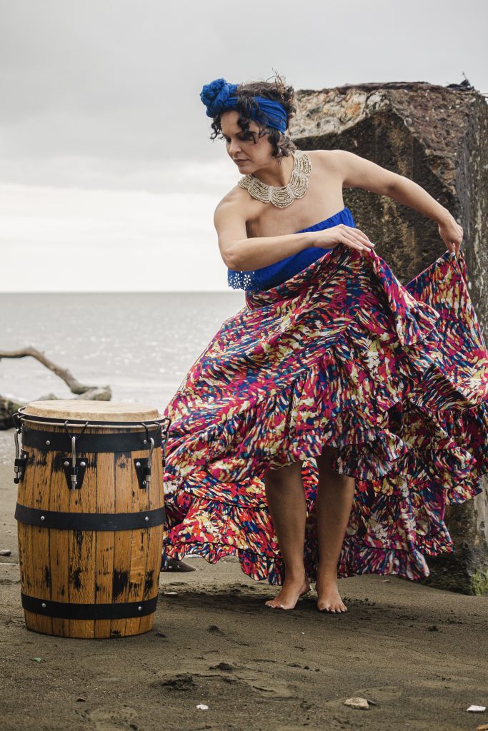 Woman dancing Bomba in front of a barrel at the beach