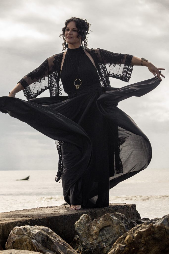 Mujer bailando con un vestido negro de Bomba en la playa