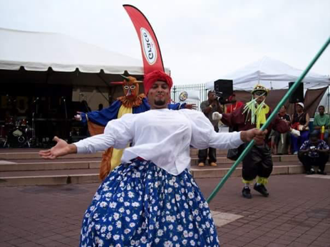 A man dressed as a festival character dancing down a street