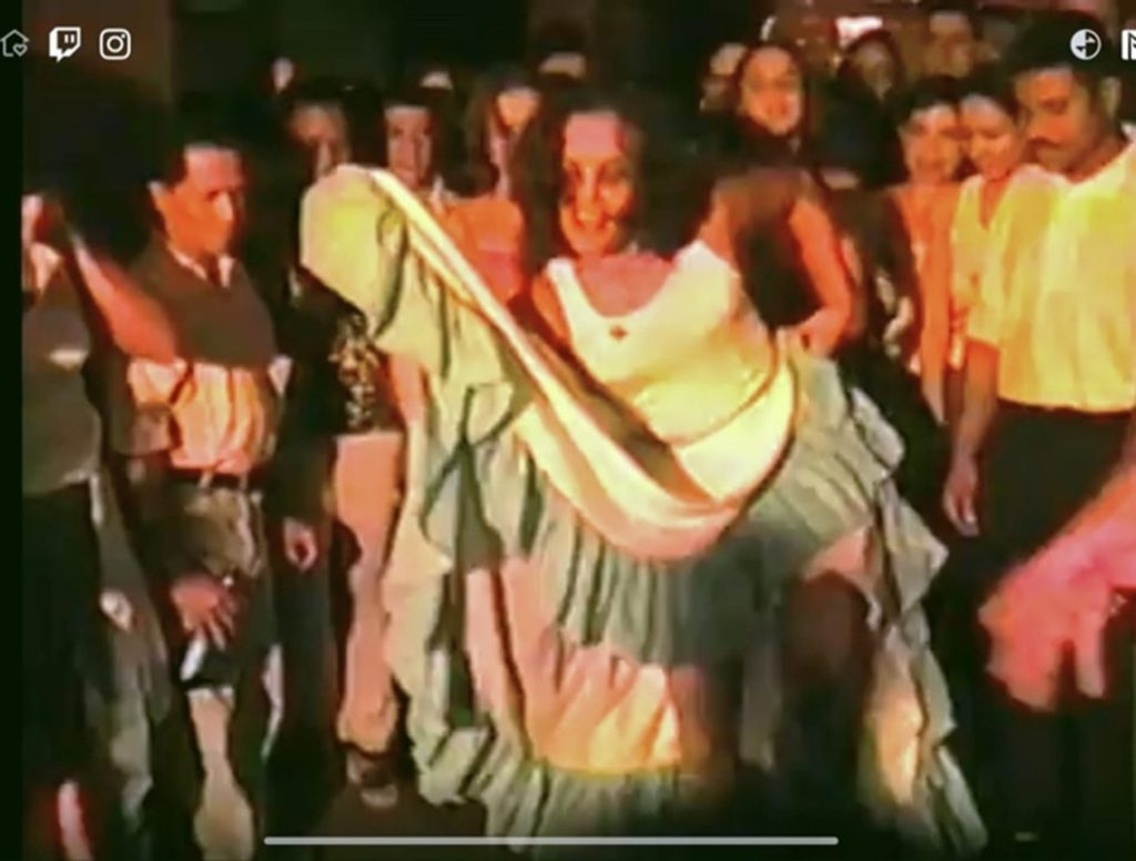 Woman dancing Bomba with her skirt amidst a crowd of people.