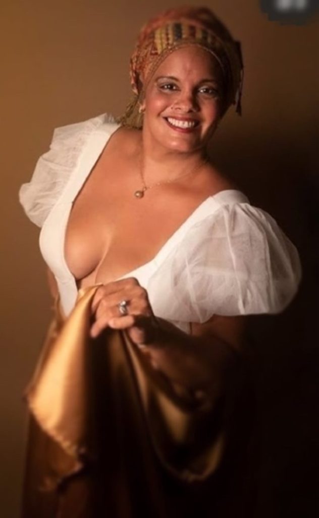 A woman posing in a white and gold Bomba ensemble.