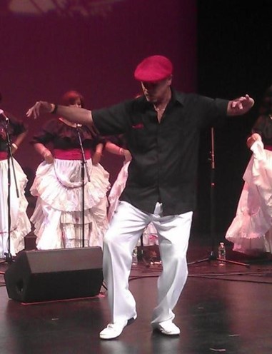 Man dancing Bomba on a stage in front of female singers