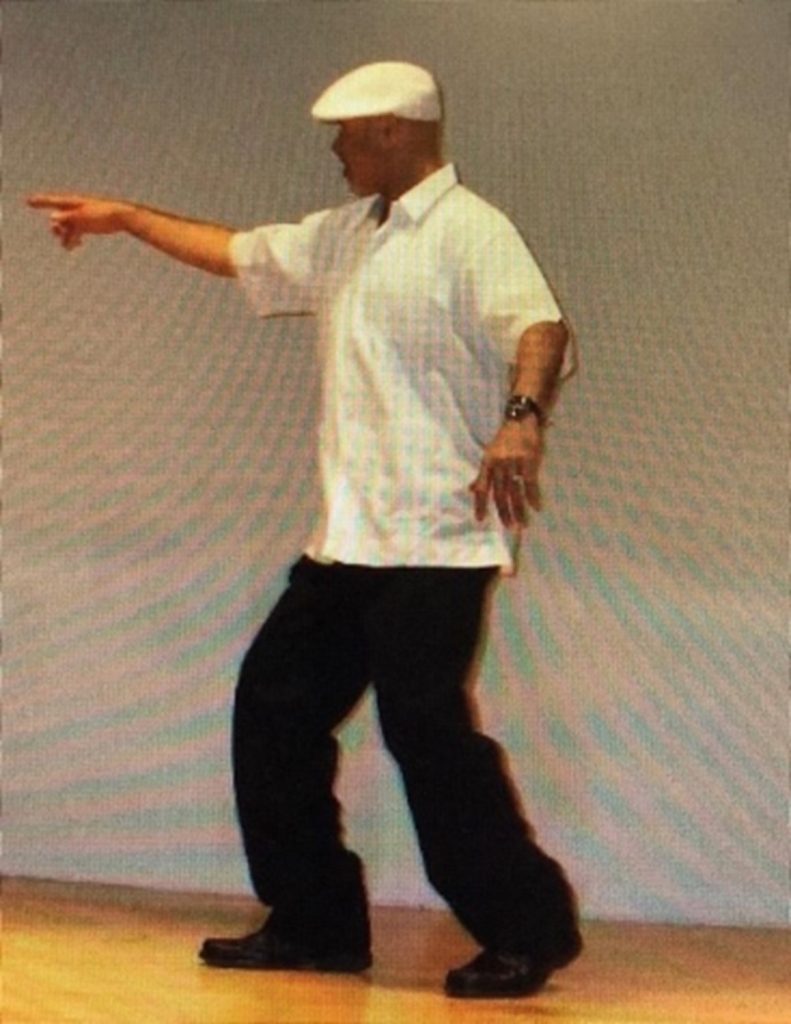 Man dancing in a white blouse pointing to the left