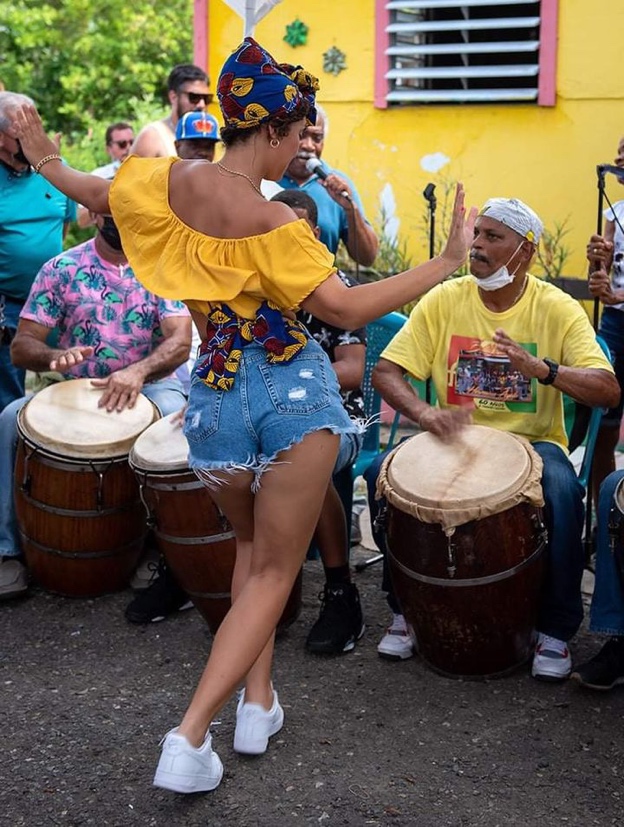 Woman dancing in front of men playing the Bomba barrels