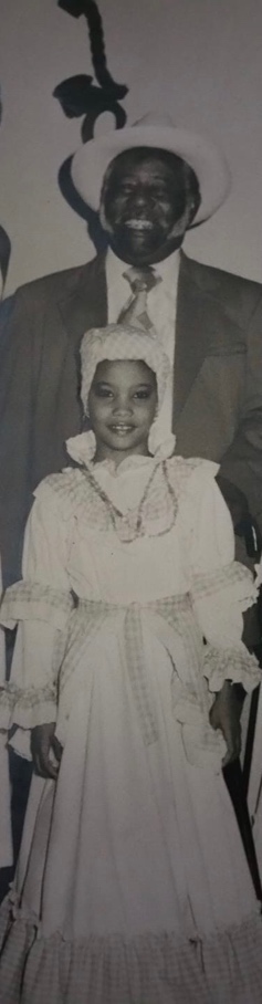 A little girl wearing a white Bomba dress in front of an older man