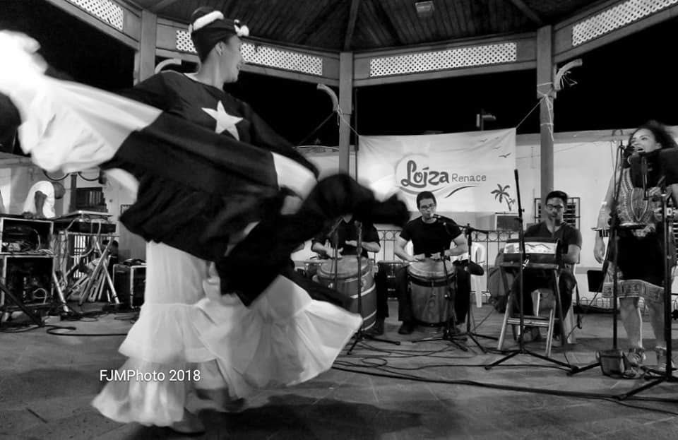 Una artista femenina bailando en el escenario frente a músicos.