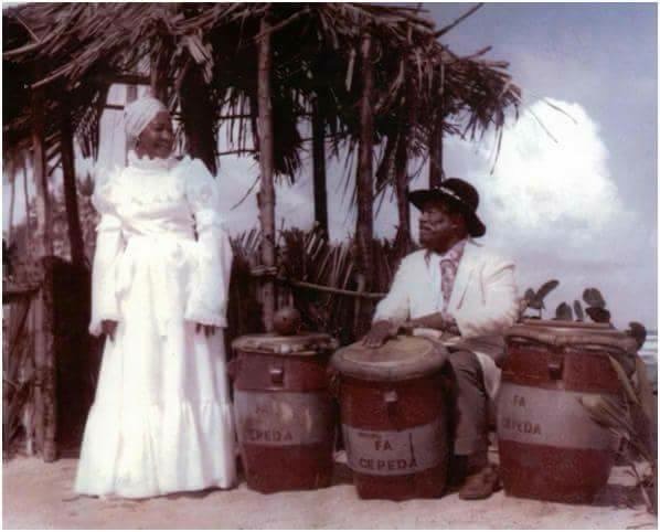 A man and a woman at the beach with barrels in white Bomba outfits