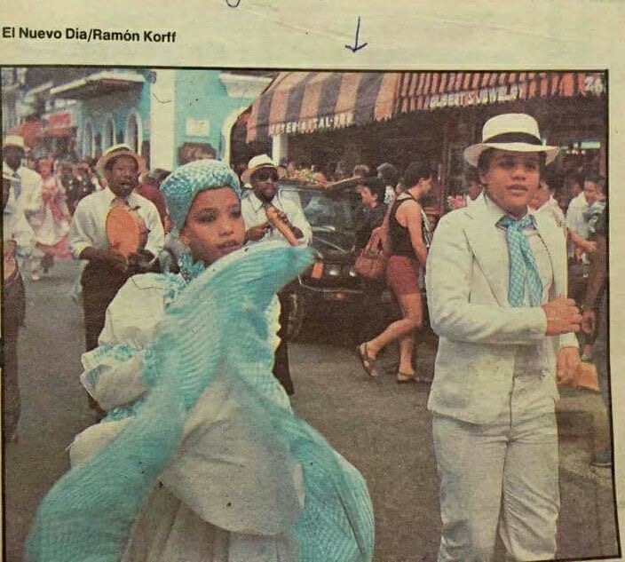 Imagen de periódico de dos niños pequeños vestidos con trajes de Bomba en un desfile.