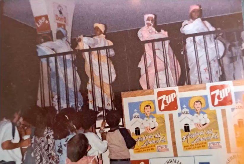 A group of people dancing Bomba behind a railing