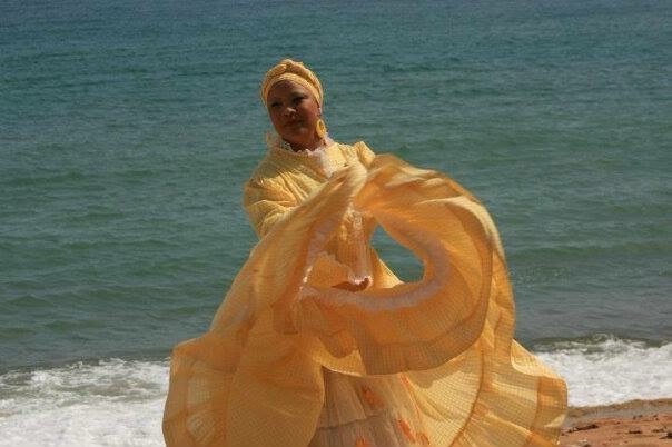 A woman in a yellow Bomba dress on a beach