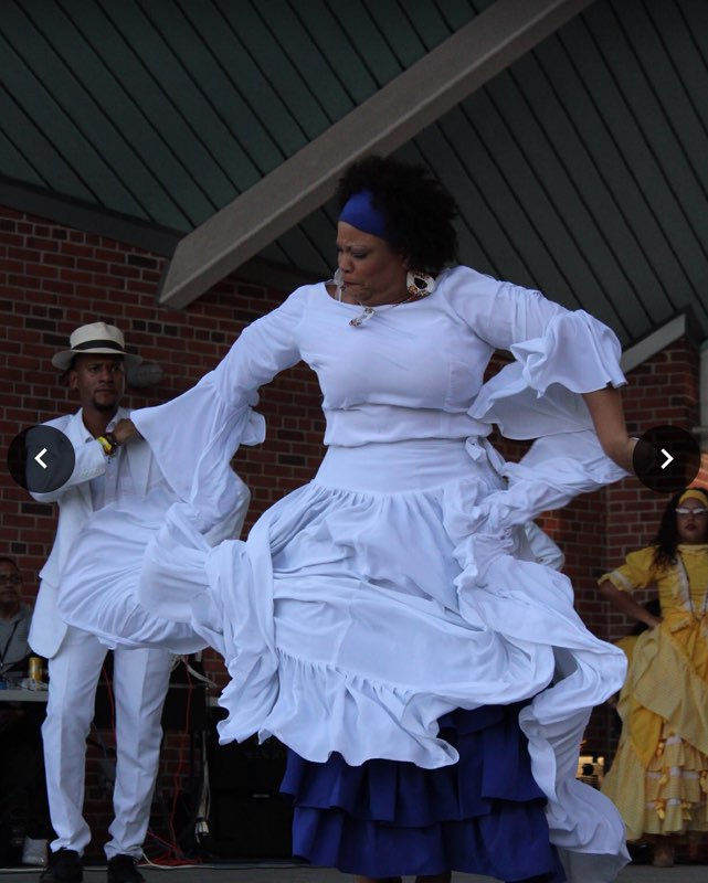 Woman dancing Bomba on stage in a white Bomba outfit