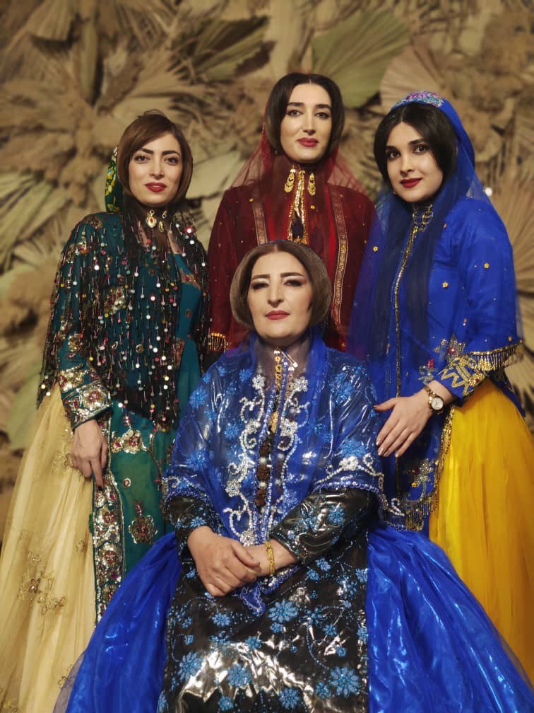 Four women posing while wearing elaborate clothing. The clothing is embellished with beads and sequins.