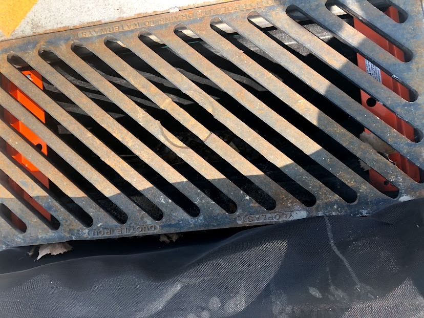 Storm drain with a black bag catching eroding sediment.