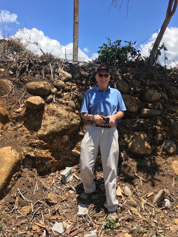 ISU professor Lee Burras standing next to a bank approximately his height consisting of large rounded rocks.