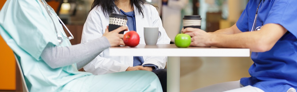 Group of doctors in the cafeteria eating lunch and talking.