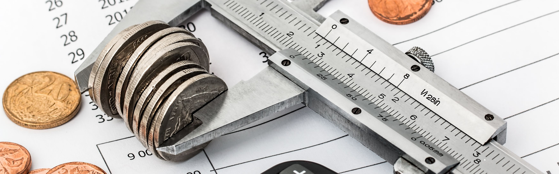 Coins measured with caliper on financial documents.