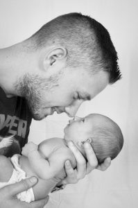 a man holding an infant close to his face and smiling