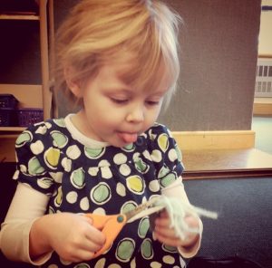 A child cutting yarn with scissors