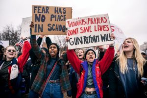 A photo of young adults holding signs protesting for gun laws at the White House