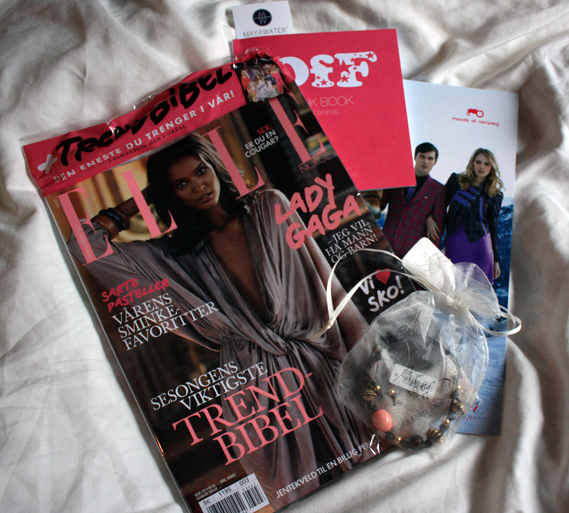Copies of the fashion magazine ELLE, with other freebies from a fashion show, strewn on sheets.
