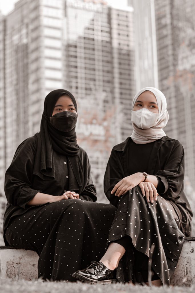 Two young women posting in black-and white hijabs, with matching tops and long, polka dot skirts.