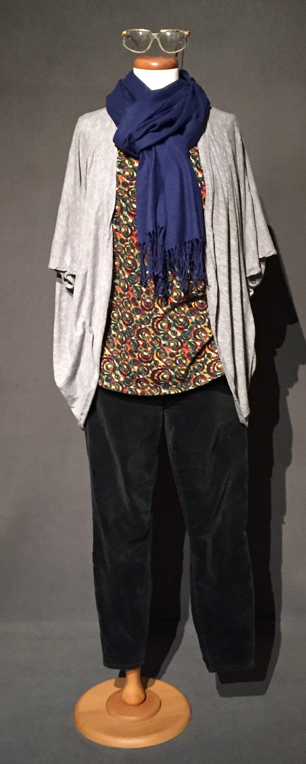 Heather gray cardigan, colorful floral top, blue scarf, and black corduroys