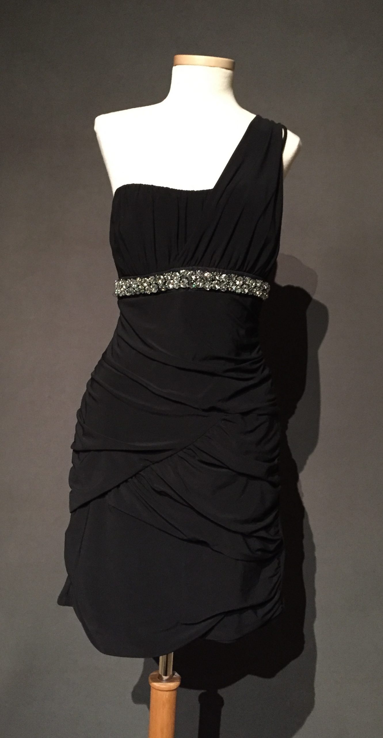 One-shoulder ruched black occasion dress with rhinestone belt resting high on the waist