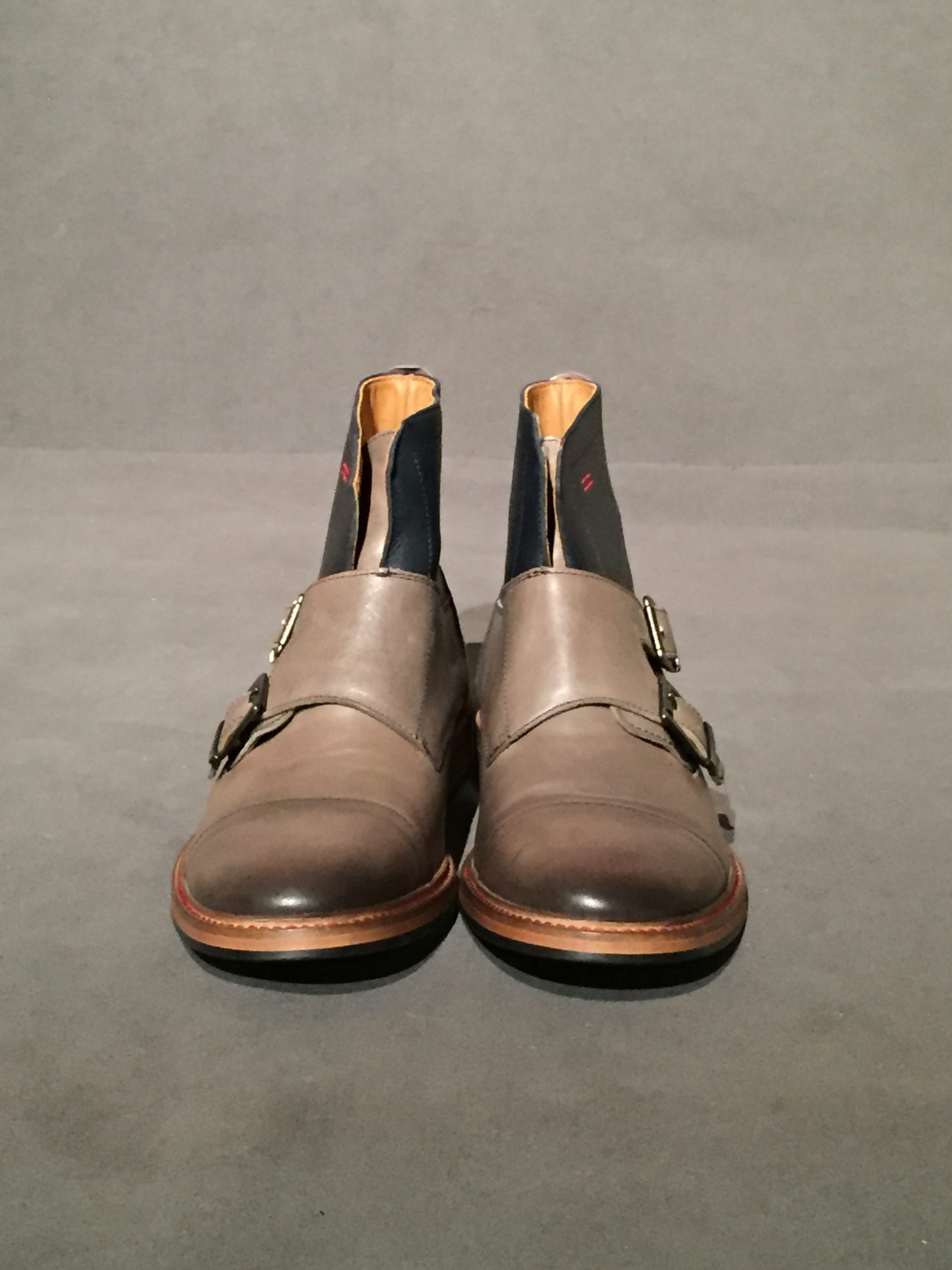Front view of two-tone grey and blue chelsea boots with side buckles