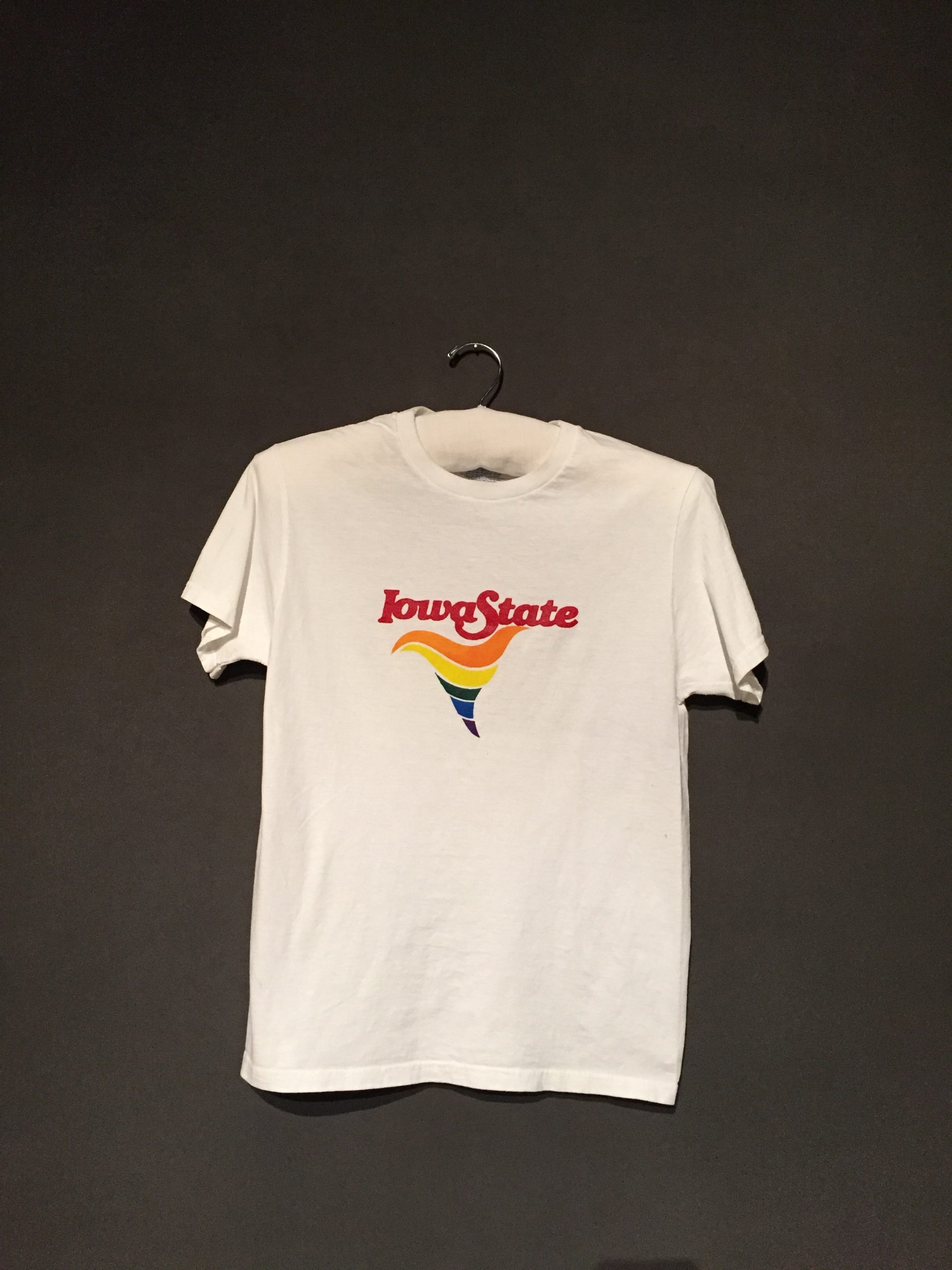 White short sleeve t-shirt with red text reading: "Iowa State" with a rainbow cyclone underneath