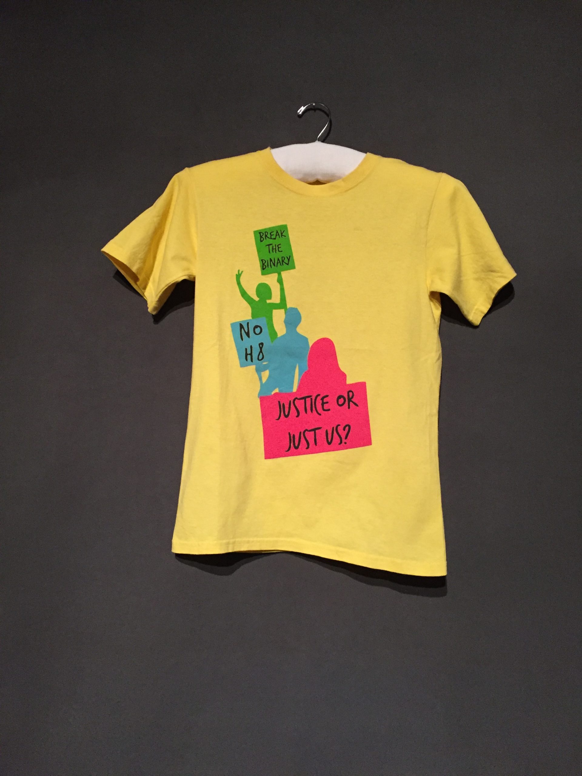 Yellow short sleeve t-shirt with protestor silhouettes in green, blue, and pink with signs reading in black text: "Break the Binary", "No H8", and "Justice or Just Us?"