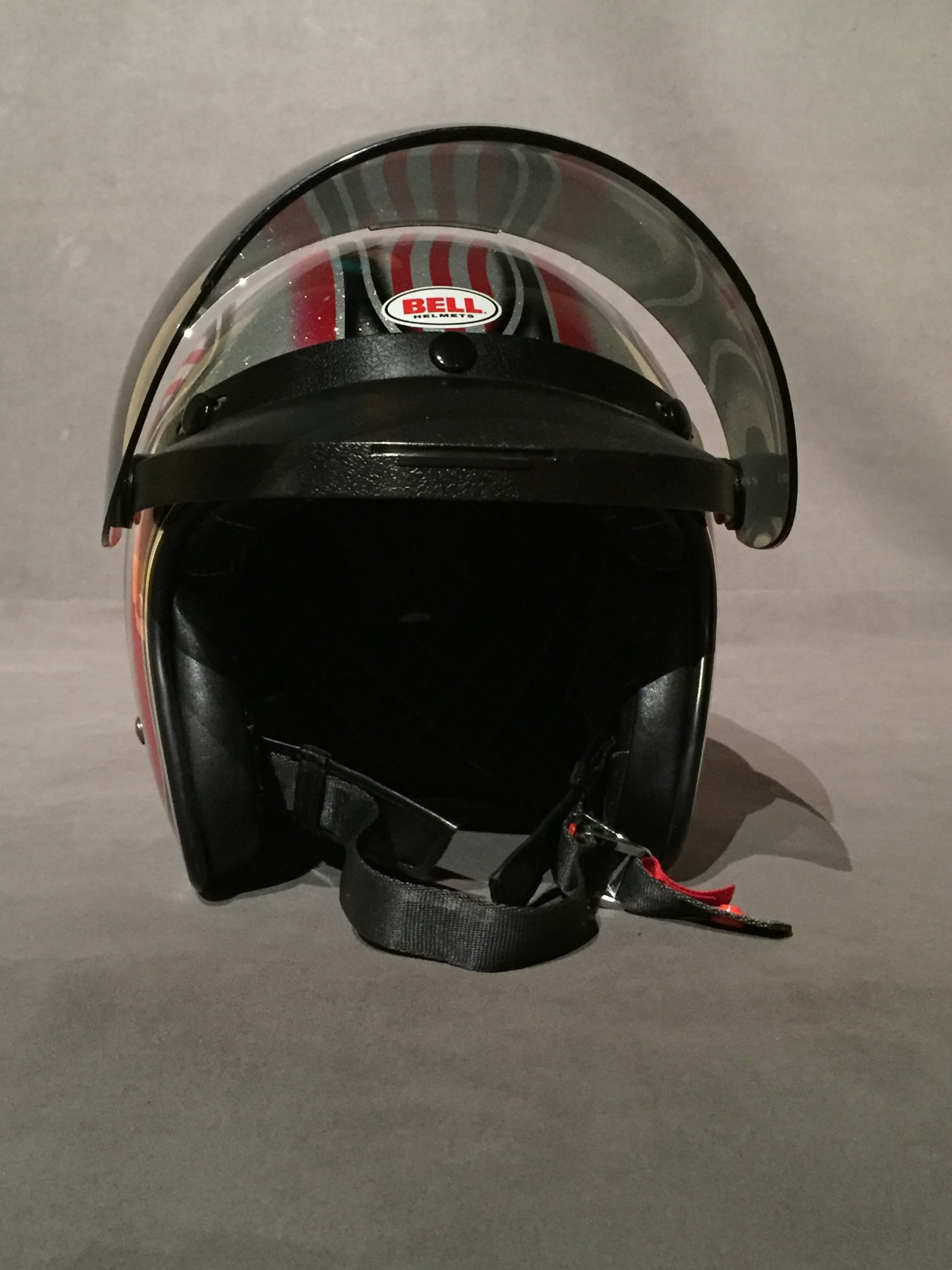 Red and silver motorcycle helmet with black visor raised.