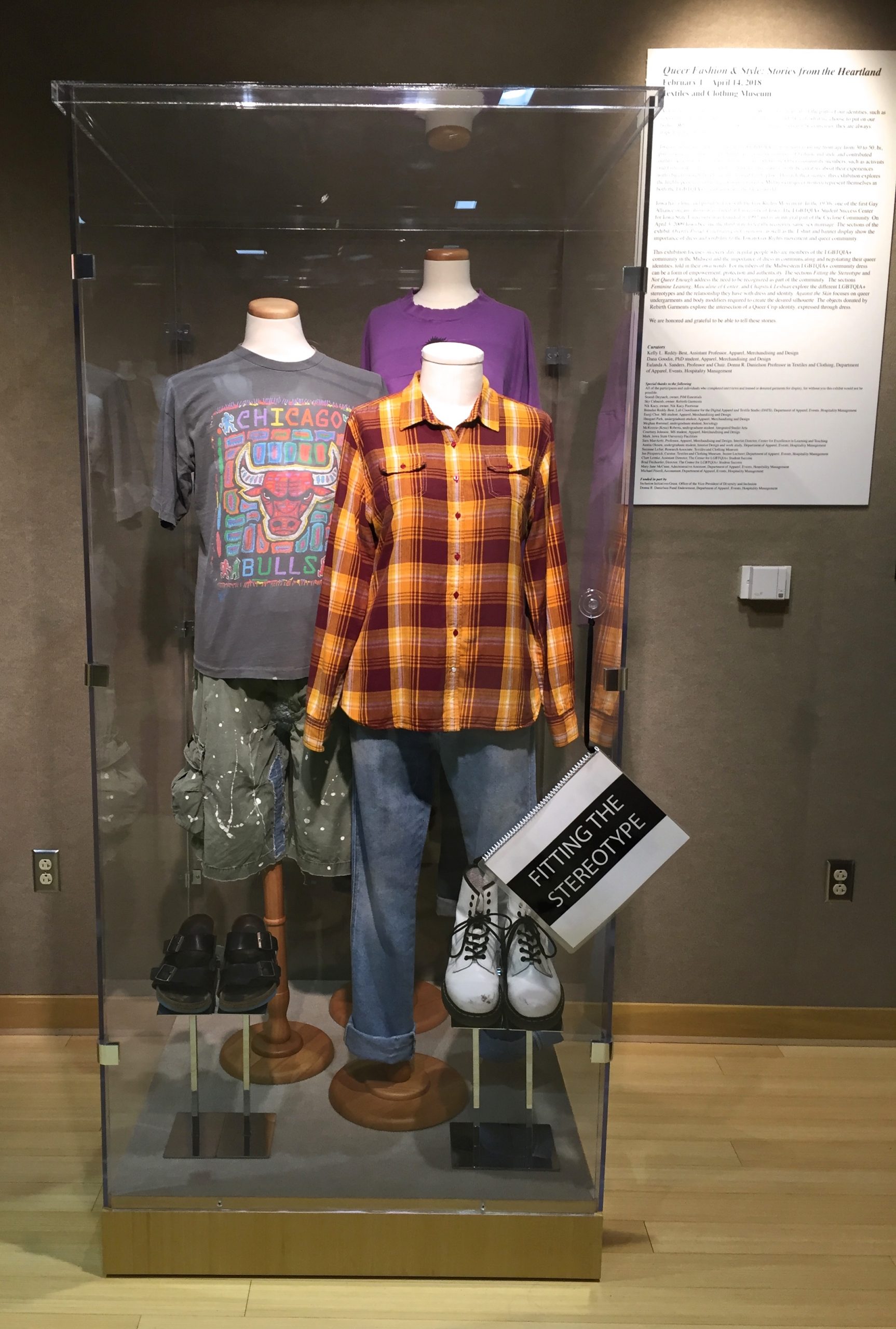 Glass case featuring dress forms wearing outfits from "Fitting the Stereotype".