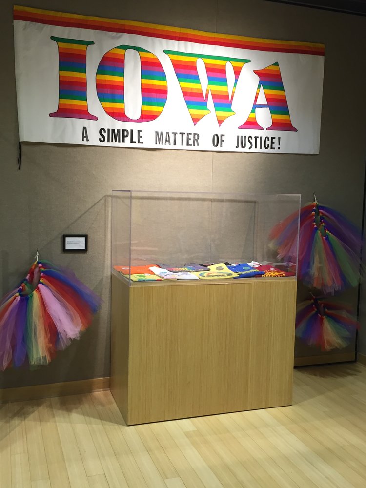 "Iowa: A Simple Matter of Justice" banner, "Overtly Proud" t-shirt and button case, and rainbow tutus