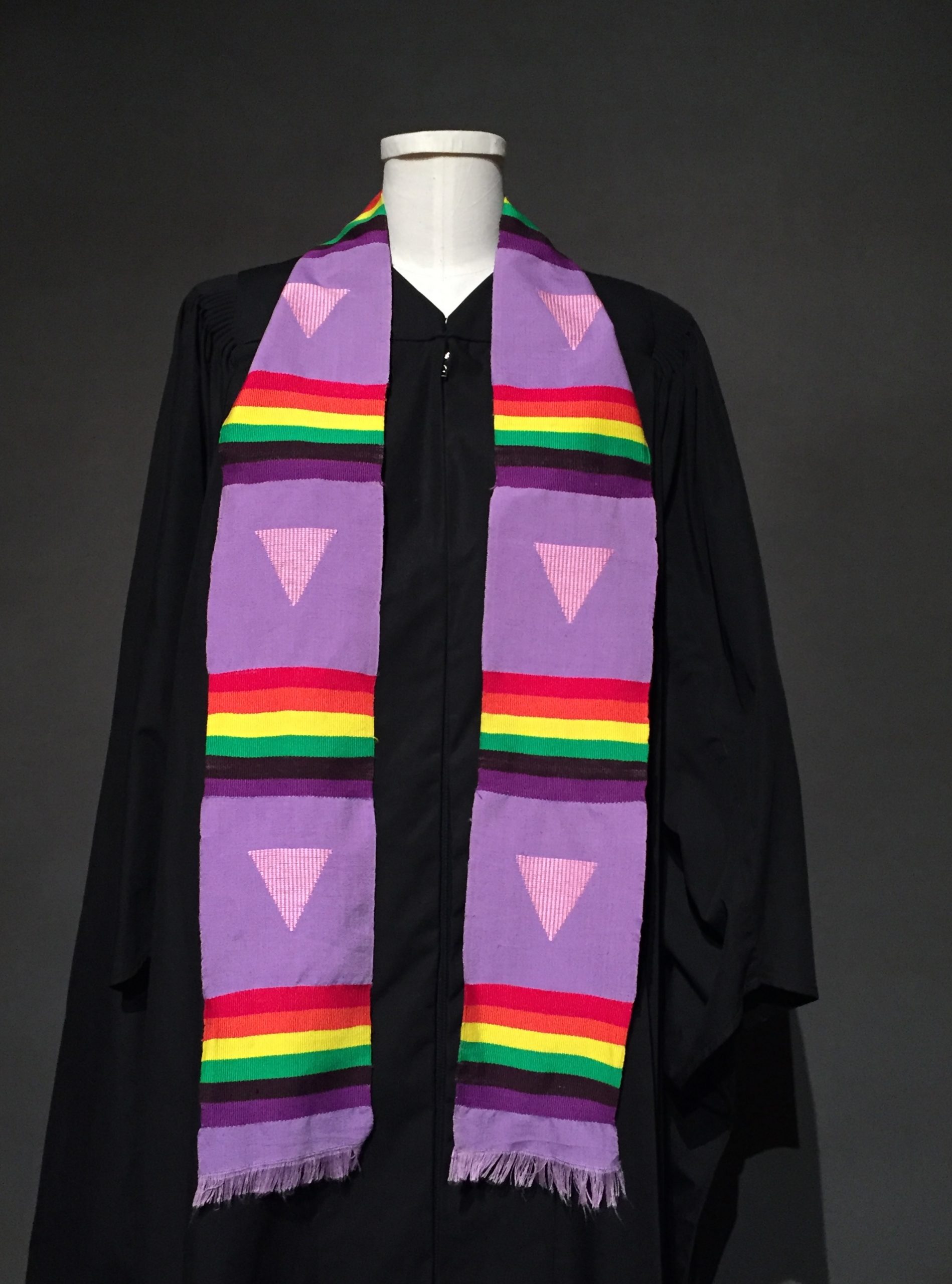 Black graduation robe, lavender graduation stole with triangle motif and rainbow bands