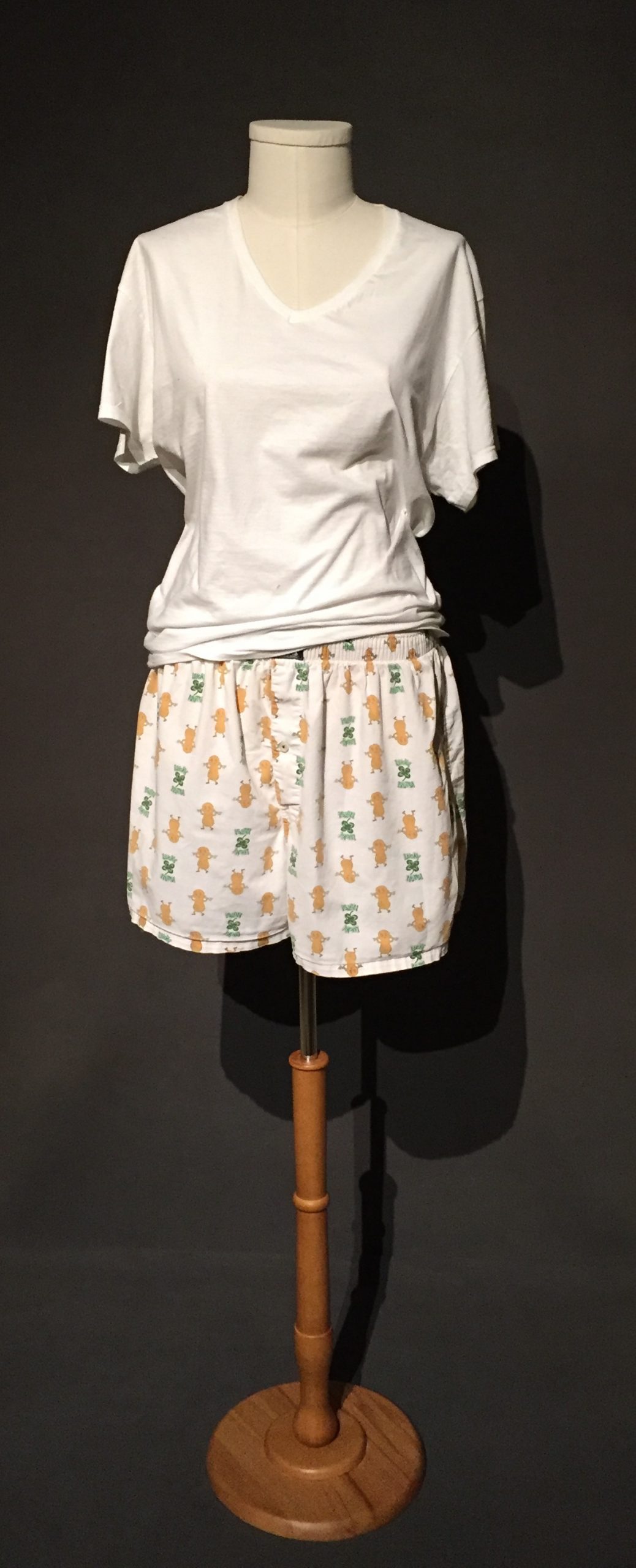 White boxer shorts with print featuring peanuts and four-leaf clovers with text reading: "Lucky Nuts" paired with white t-shirt