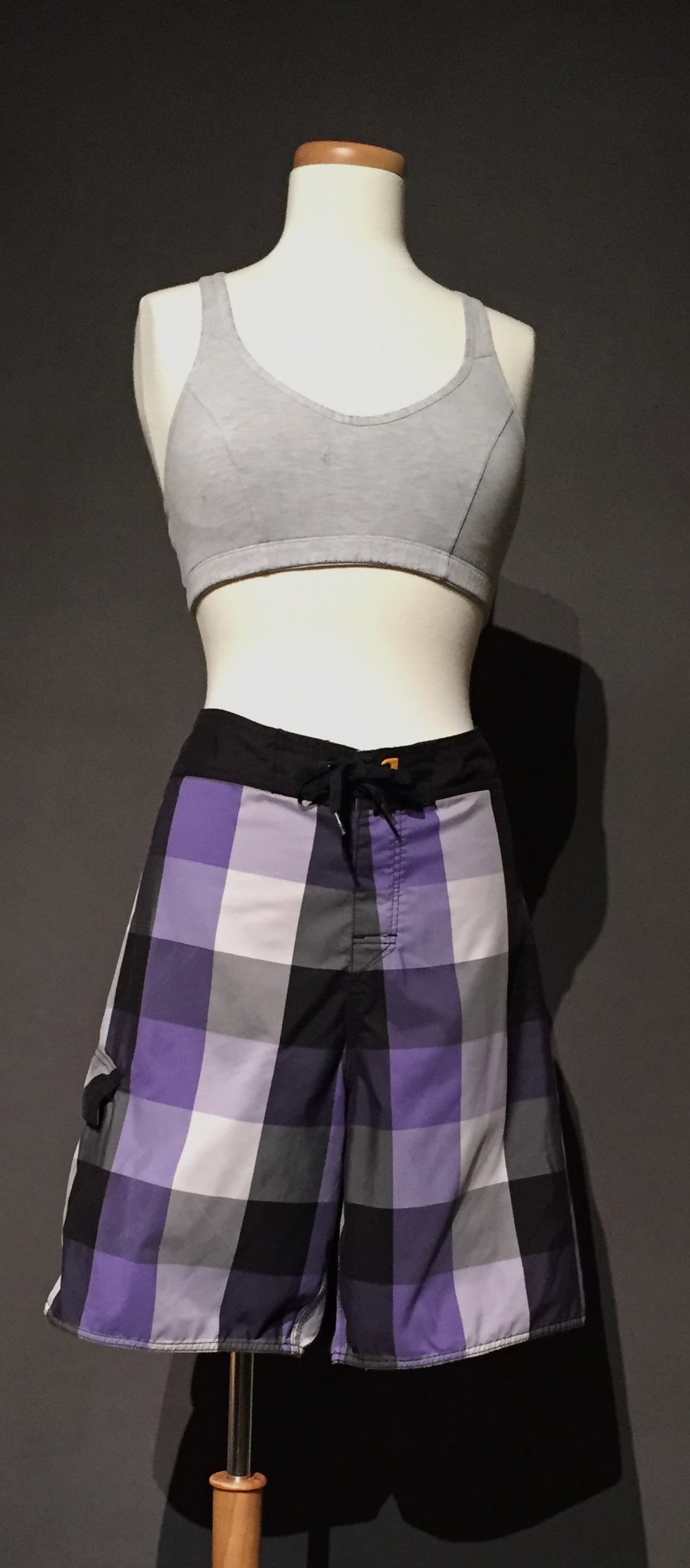 Purple and black plaid swim trunk paired with grey sports bra