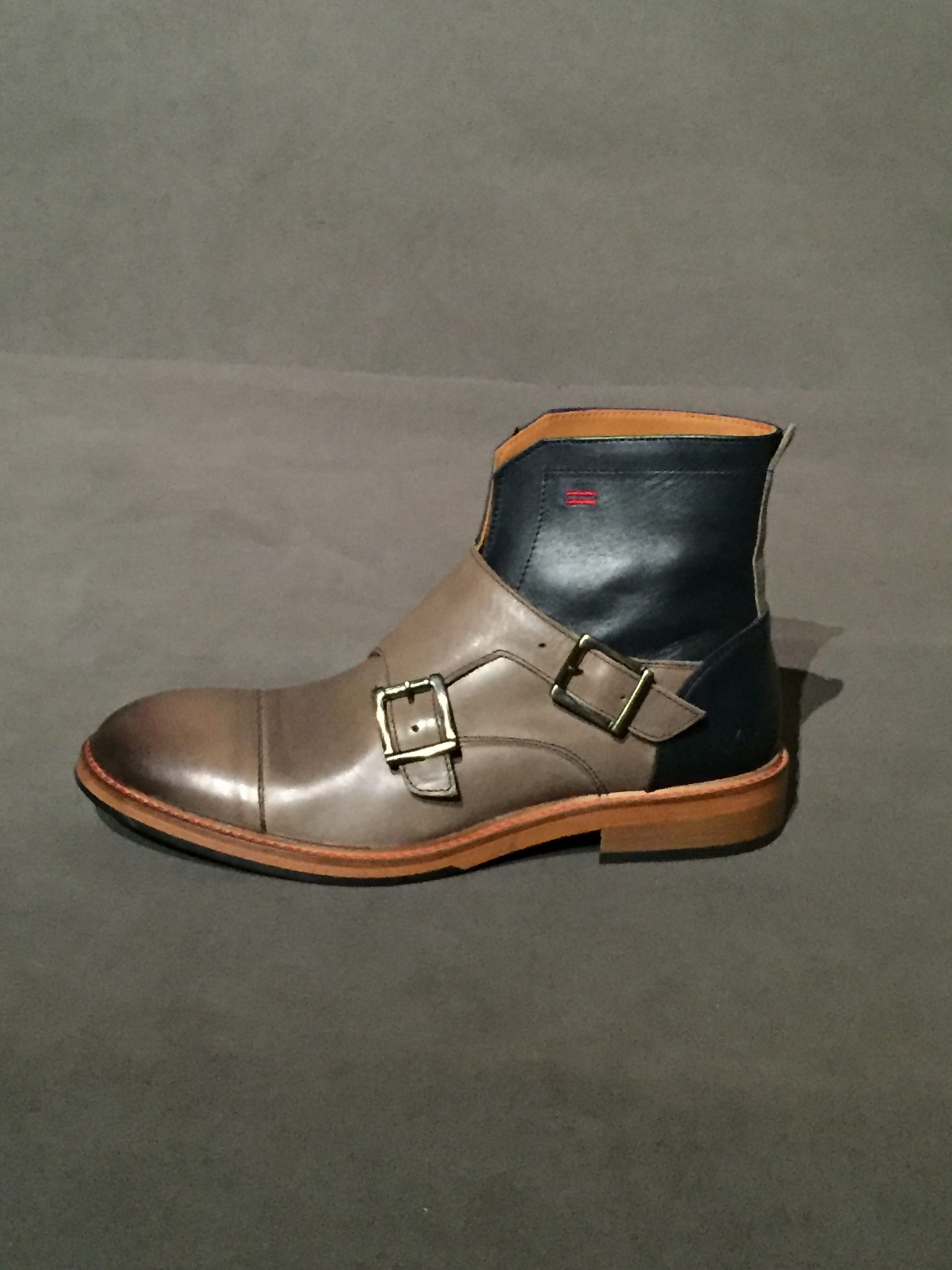 Side view of two-tone grey and blue chelsea boot with side buckle