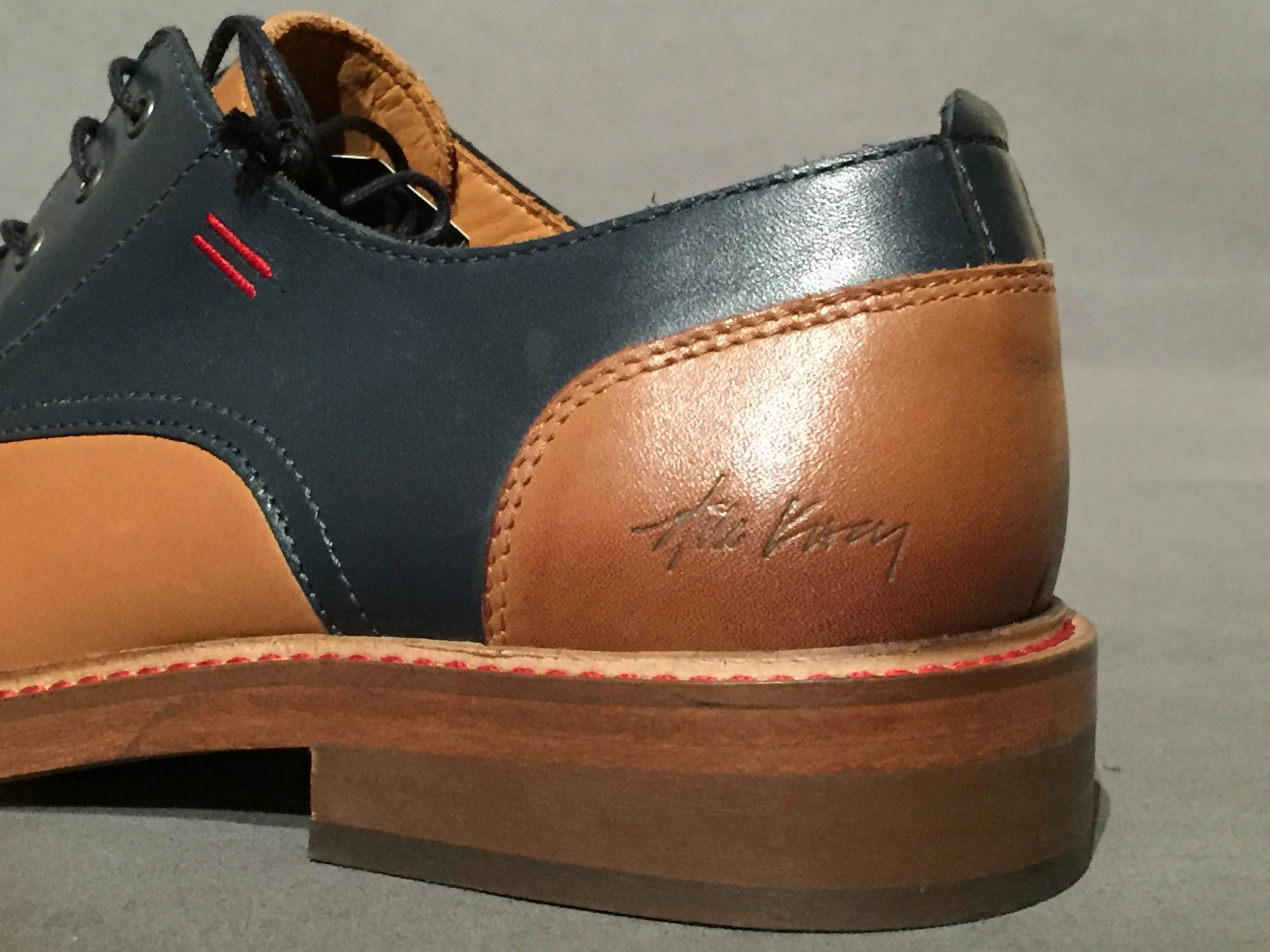 Close-up of Nik Kacy imprint on side of two-tone brown and navy oxford shoes