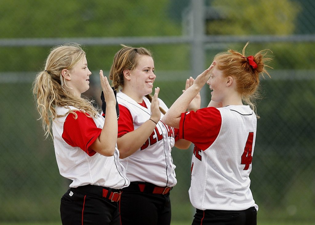 Girls wearing sports jerseys giving high fives