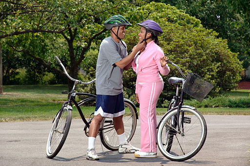A photo of a couple putting on helmets before a bicycle ride.