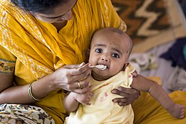 Most children are introduced to solid foods around six months old, like this girl who is having her first taste of rice.