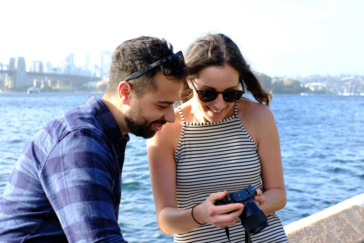 Photo of a young couple looking at photos taken on a camera.
