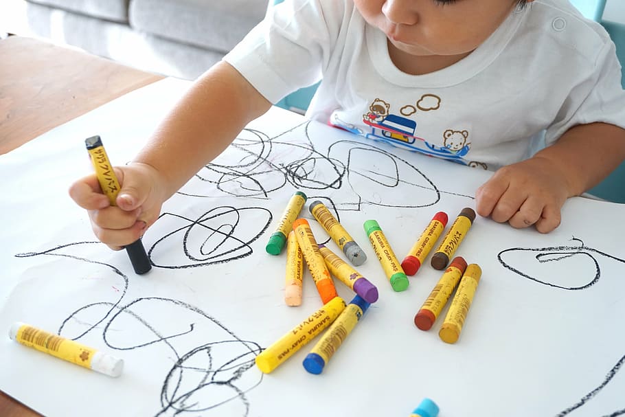 A photo of a toddler drawing random shapes on a blank sheet of paper