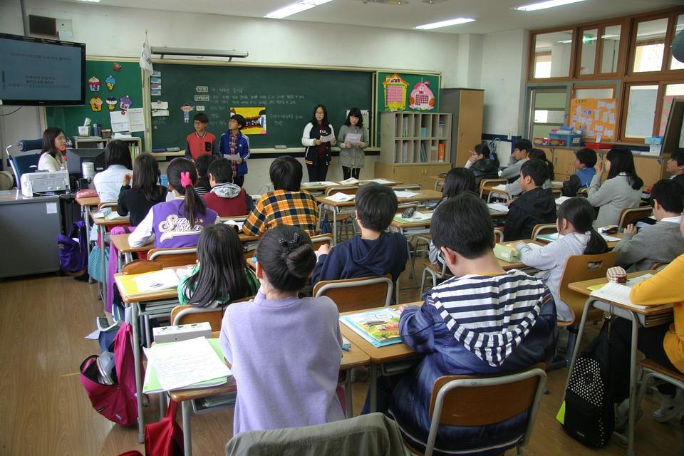 Photo of students paired up and presenting at the front of a classroom in Asia.