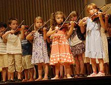 Photo of children playing at a violin recital.