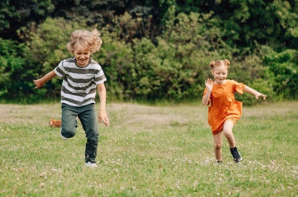Siblings running through a field.