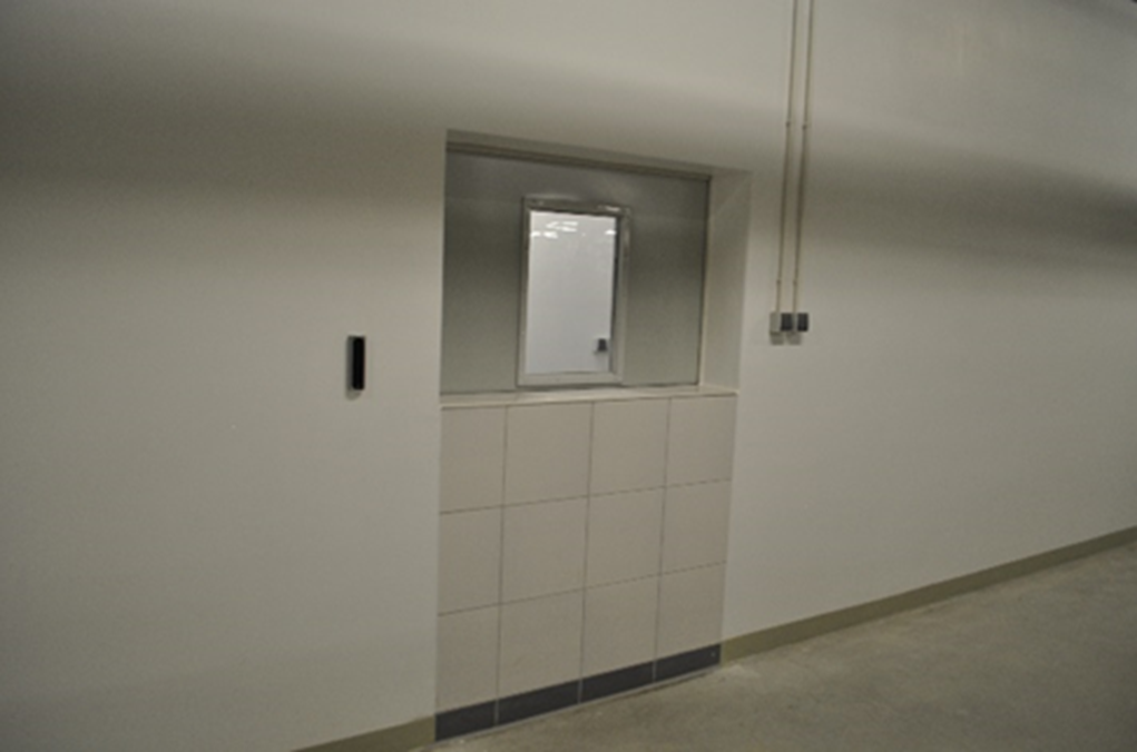 A photo of a white wall with a small window set into it.