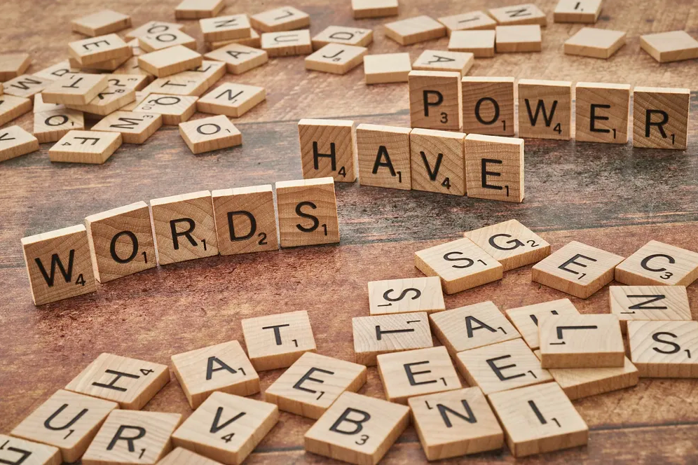 scrablle tiles scattered across a table with some spelling "words have power."