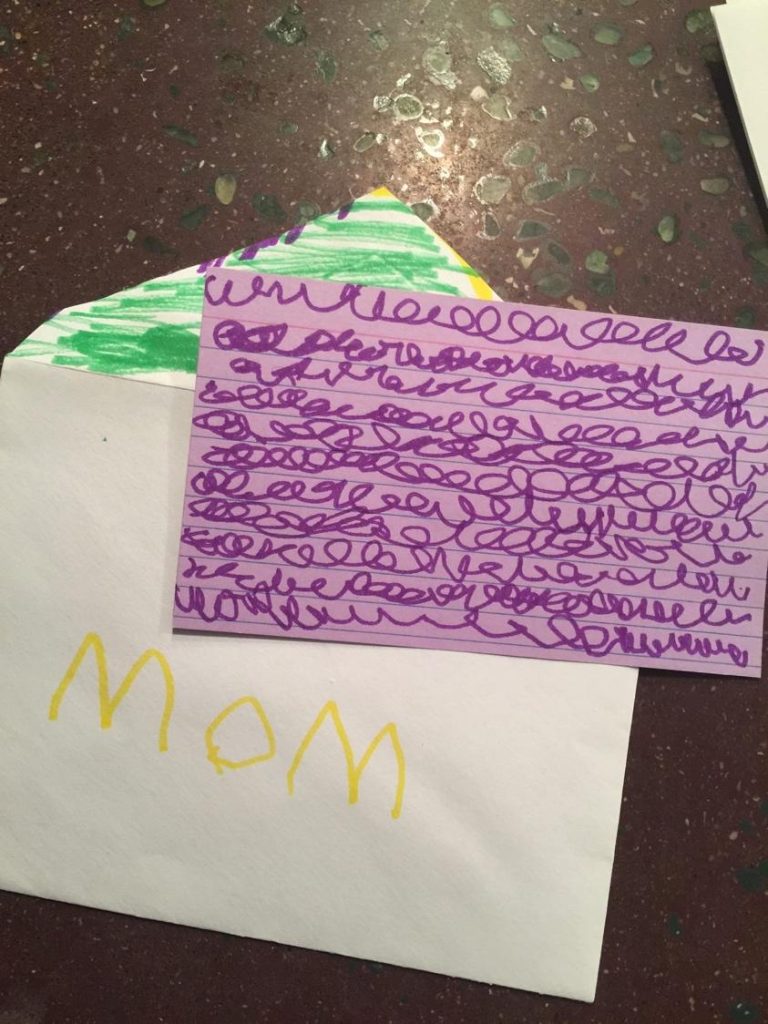 "Mom" written on an envelope with squiggly lines on a notecard.